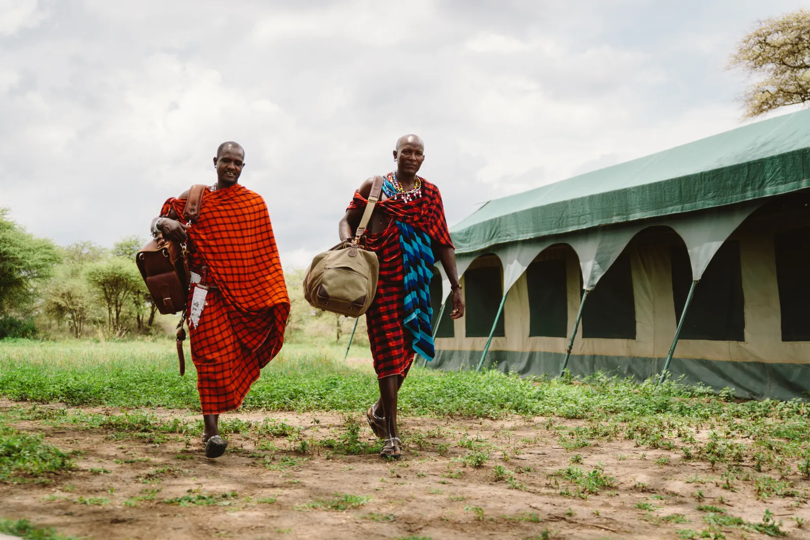Two Maasai guides walking past the tents