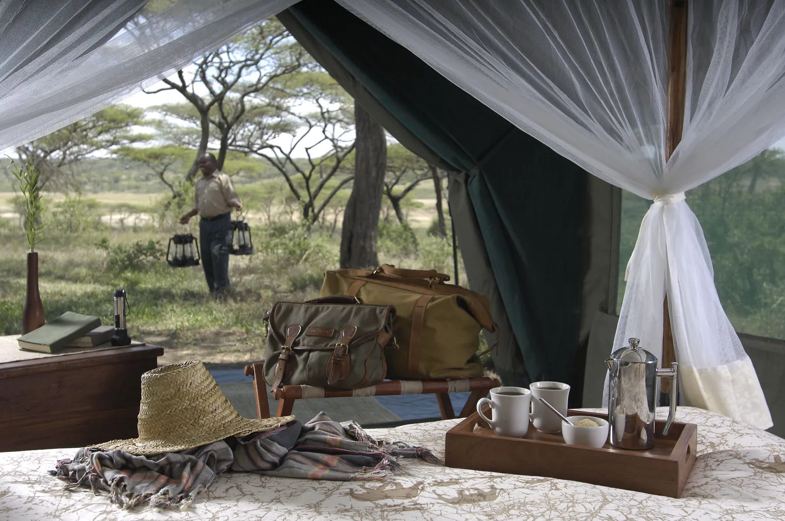 Morning coffee in a Serengeti camp tent, a guide passing outside